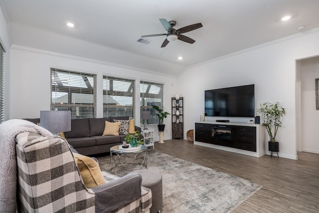 living area with visible vents, wood finished floors, crown molding, baseboards, and vaulted ceiling