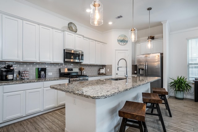 kitchen with a sink, crown molding, visible vents, and stainless steel appliances