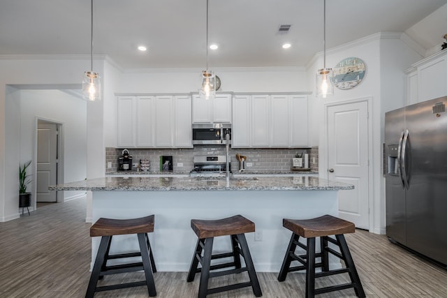 kitchen with visible vents, light wood-style flooring, a kitchen breakfast bar, backsplash, and stainless steel appliances