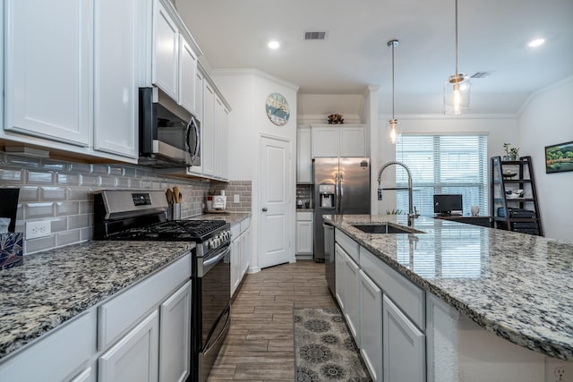 kitchen with visible vents, a sink, backsplash, wood finished floors, and appliances with stainless steel finishes