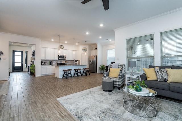 living room featuring recessed lighting, wood finished floors, a ceiling fan, and ornamental molding