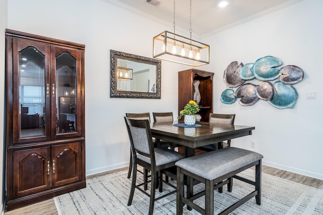 dining space featuring light wood-type flooring, baseboards, and crown molding