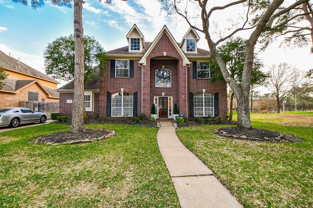 view of front of home featuring a front yard, fence, and brick siding