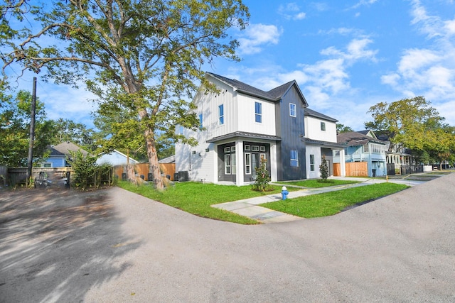 modern farmhouse style home with board and batten siding, a front yard, and fence