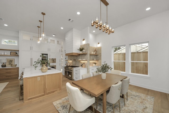 dining space with visible vents, baseboards, recessed lighting, a towering ceiling, and light wood-type flooring