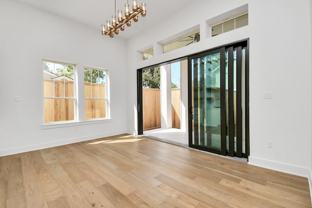 spare room with a notable chandelier, wood finished floors, and baseboards