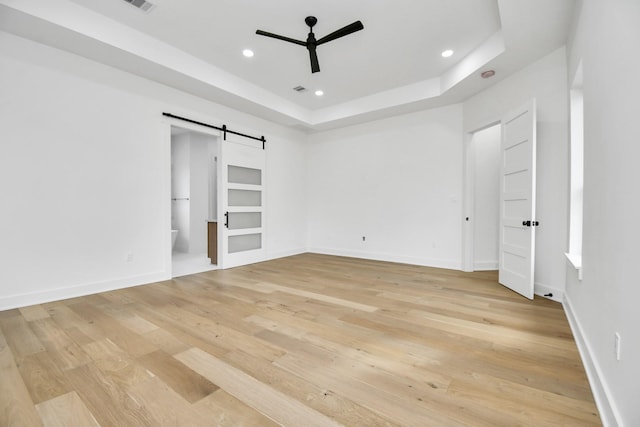 unfurnished bedroom with recessed lighting, baseboards, light wood-type flooring, and a barn door