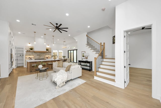 living area with visible vents, light wood-style flooring, recessed lighting, ceiling fan, and stairs