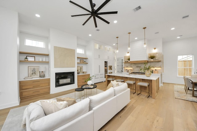 519 Railey St, Houston, TX 77009 - living area with a glass covered fireplace, recessed lighting, a ceiling fan, light wood-type flooring, and a towering ceiling