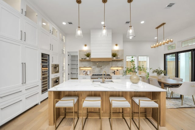 kitchen featuring visible vents, backsplash, light wood-style flooring, and white cabinetry