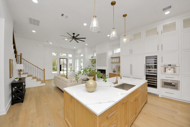 kitchen featuring a kitchen island with sink, visible vents, a fireplace, and a sink