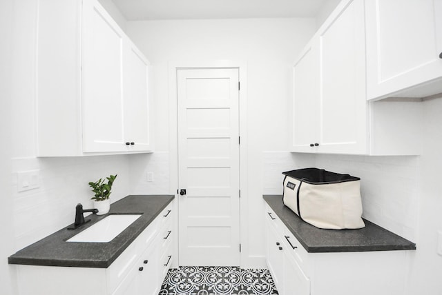 kitchen featuring decorative backsplash, white cabinets, and a sink