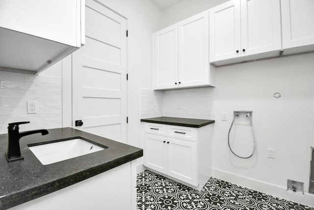 washroom with baseboards, hookup for an electric dryer, cabinet space, a sink, and washer hookup