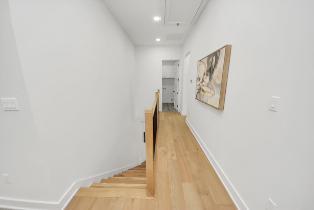 hall with light wood-type flooring, an upstairs landing, recessed lighting, baseboards, and attic access