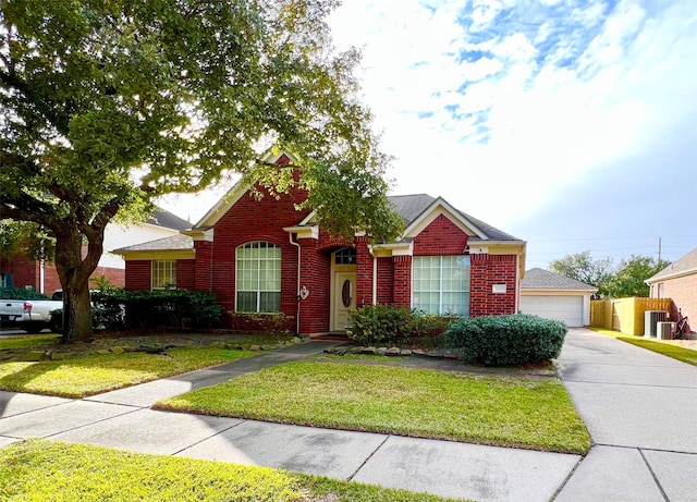 view of front of property featuring a front yard, fence, brick siding, and a detached garage