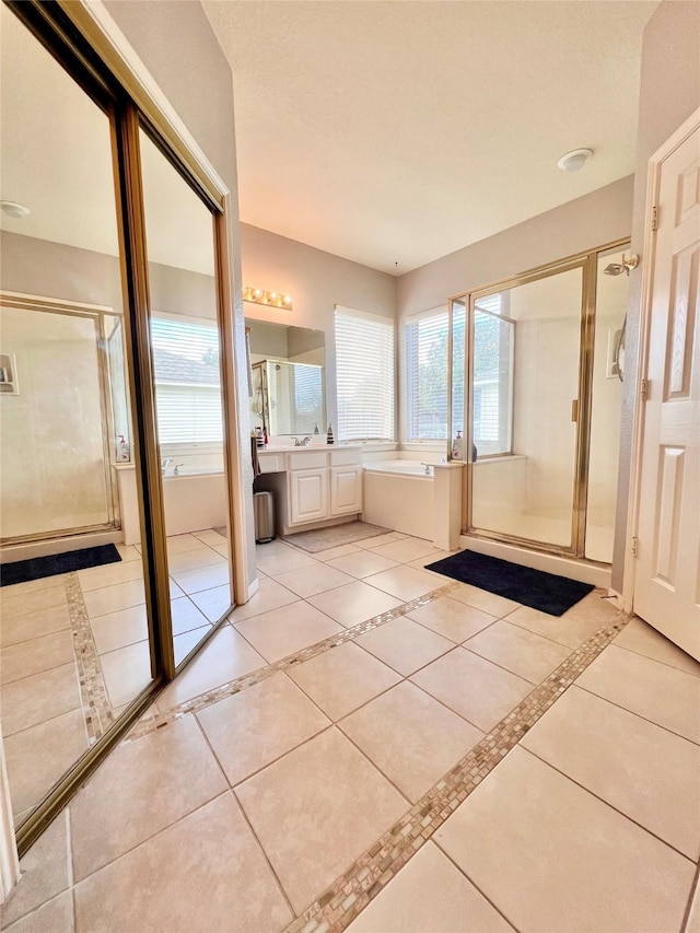 bathroom featuring tile patterned flooring, a shower stall, a bath, and vanity