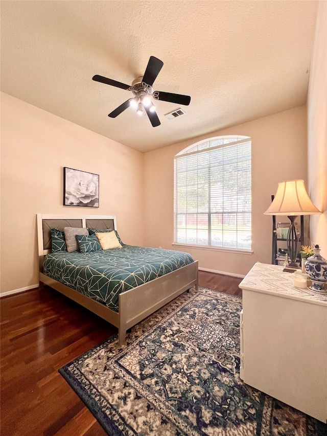 bedroom featuring a textured ceiling, wood finished floors, visible vents, and baseboards