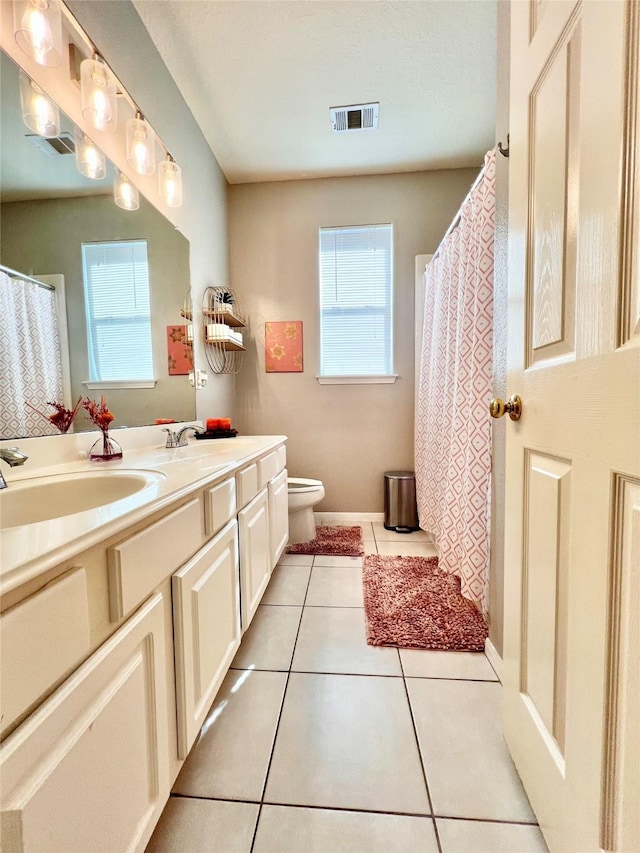 bathroom featuring visible vents, double vanity, a sink, tile patterned floors, and toilet