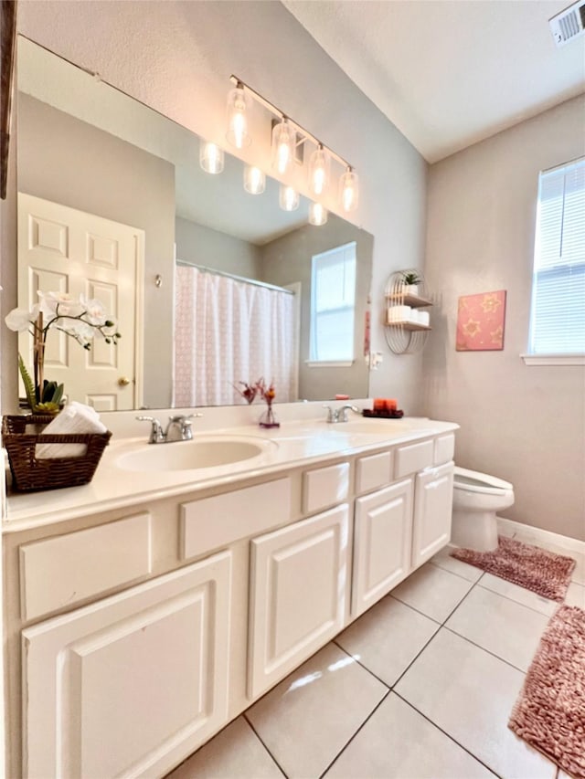 bathroom with visible vents, double vanity, a sink, tile patterned floors, and toilet