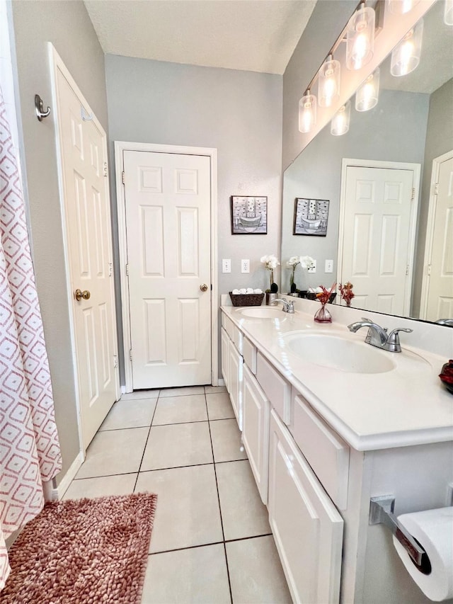 full bathroom featuring tile patterned flooring, double vanity, and a sink