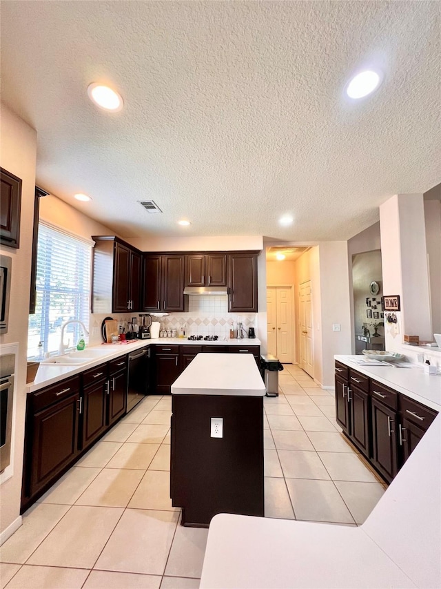 kitchen with dark brown cabinets, backsplash, a kitchen island, light countertops, and light tile patterned flooring