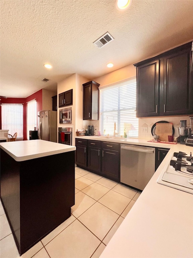 kitchen featuring visible vents, a kitchen island, light countertops, light tile patterned floors, and stainless steel appliances