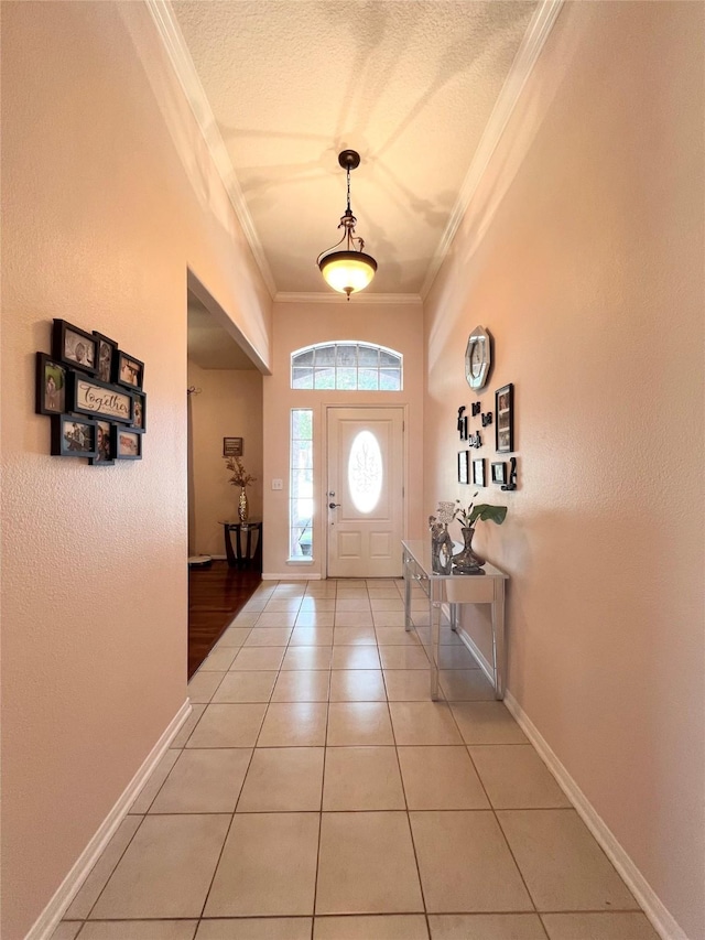 entrance foyer with a textured ceiling, light tile patterned floors, baseboards, and ornamental molding