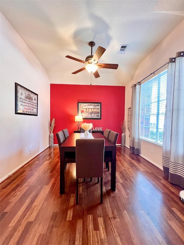 dining room with lofted ceiling, wood finished floors, visible vents, and baseboards