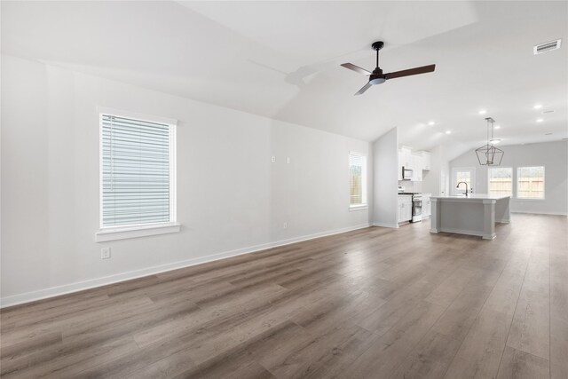 unfurnished living room with vaulted ceiling, visible vents, a healthy amount of sunlight, and wood finished floors