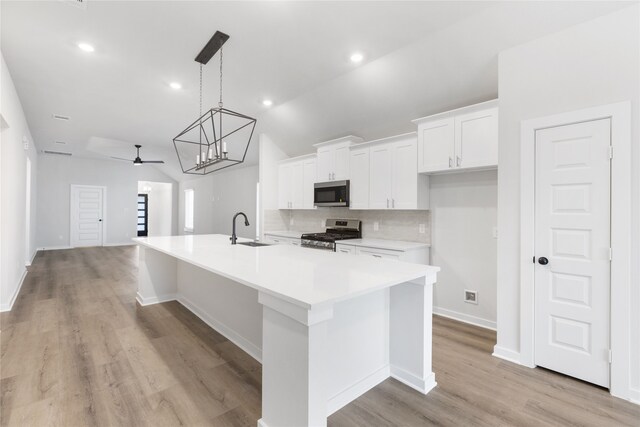 kitchen featuring light countertops, decorative backsplash, appliances with stainless steel finishes, white cabinets, and a sink