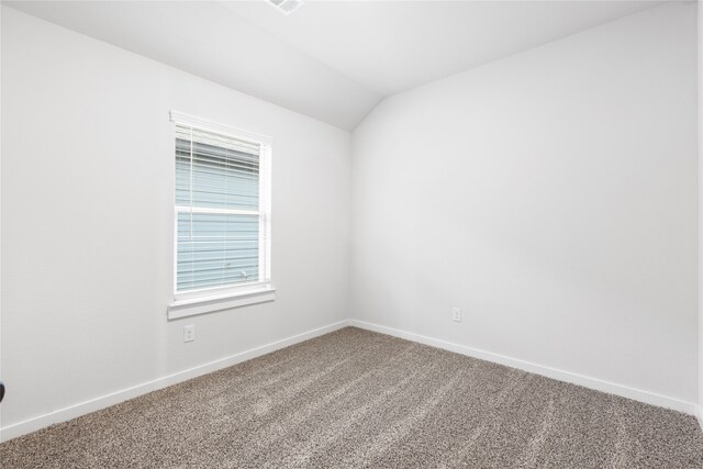 spare room with vaulted ceiling, carpet, and baseboards