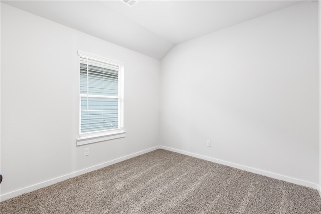 carpeted empty room with vaulted ceiling and baseboards