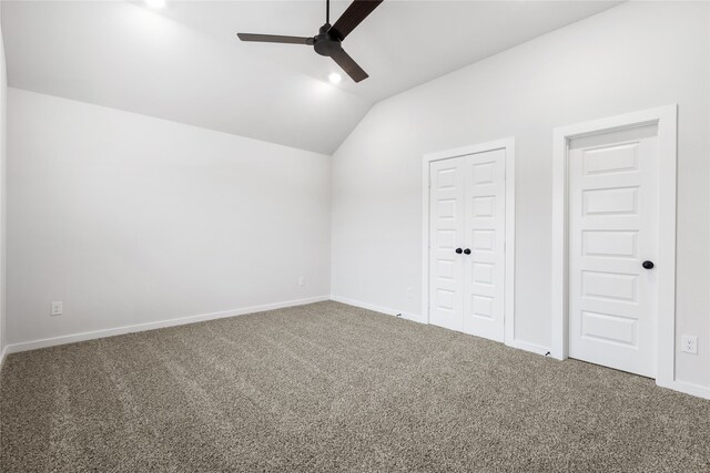 interior space with vaulted ceiling, carpet flooring, baseboards, and ceiling fan