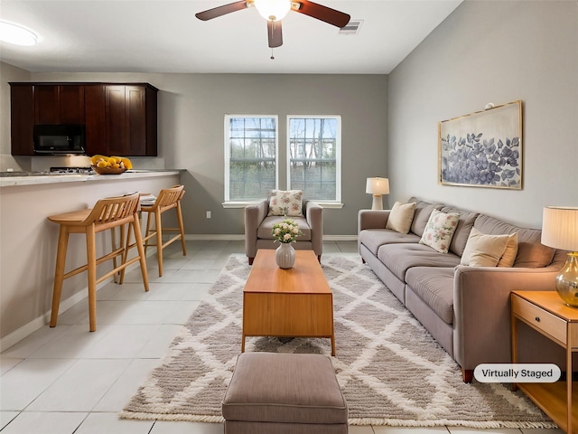 living room with light tile patterned floors, a ceiling fan, visible vents, and baseboards