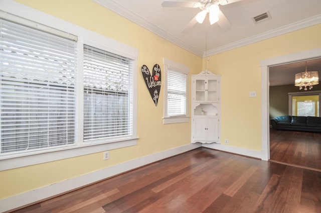 empty room featuring dark wood finished floors, visible vents, baseboards, and ornamental molding