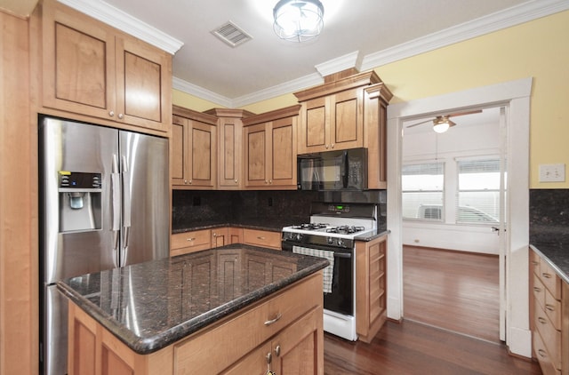 kitchen featuring tasteful backsplash, visible vents, gas range gas stove, black microwave, and stainless steel fridge