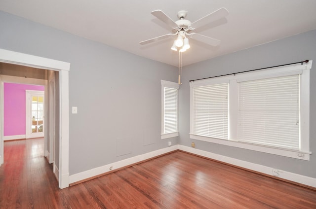 empty room with ceiling fan, baseboards, and wood finished floors