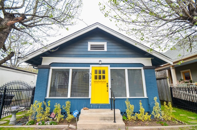 bungalow with fence, brick siding, and entry steps