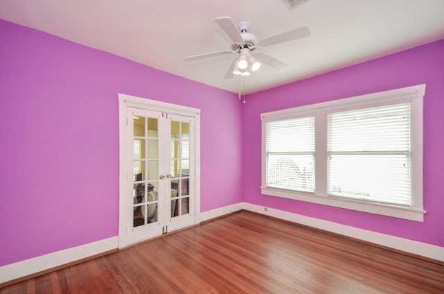 empty room with a ceiling fan, wood finished floors, baseboards, and french doors