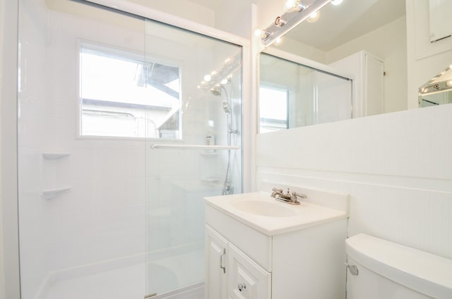 full bathroom featuring a stall shower, toilet, and vanity