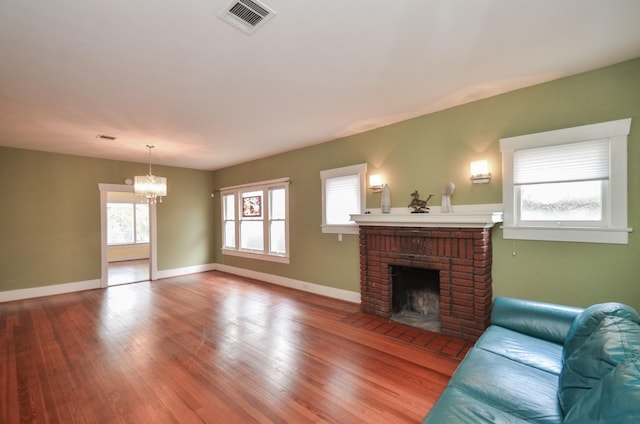 living room featuring a brick fireplace, baseboards, visible vents, and wood-type flooring