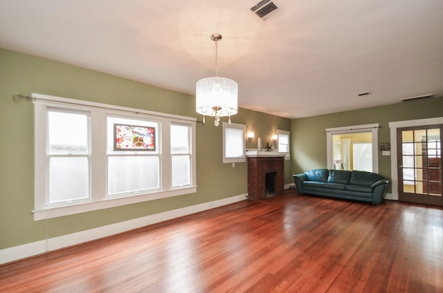 unfurnished living room featuring visible vents, a fireplace, and wood finished floors