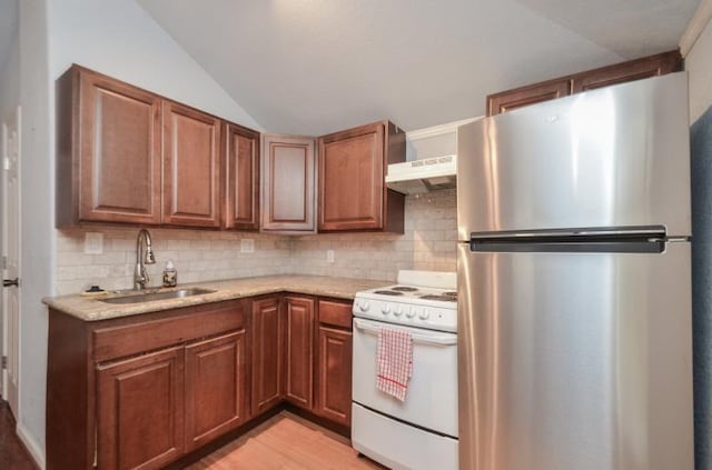 kitchen featuring under cabinet range hood, vaulted ceiling, white gas range oven, freestanding refrigerator, and a sink