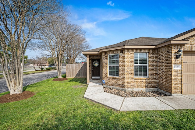 view of front of house with brick siding, a garage, a front lawn, and fence