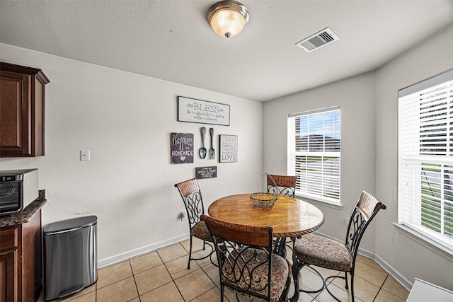 dining space featuring light tile patterned flooring, visible vents, a healthy amount of sunlight, and baseboards