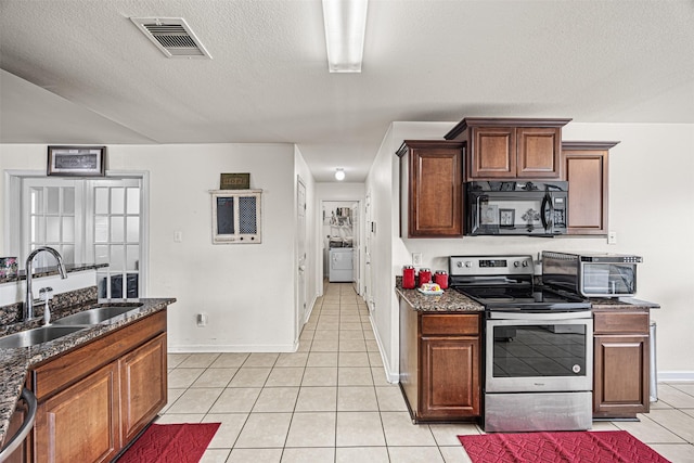 kitchen with visible vents, light tile patterned floors, appliances with stainless steel finishes, washer / clothes dryer, and a sink