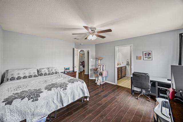 bedroom with baseboards, wood finished floors, arched walkways, a textured ceiling, and a ceiling fan