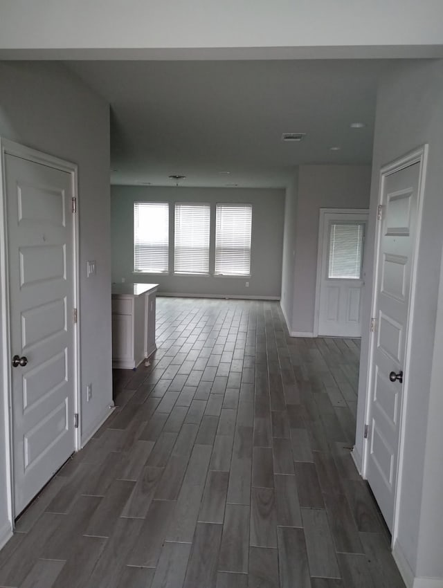 corridor with baseboards, visible vents, and wood tiled floor