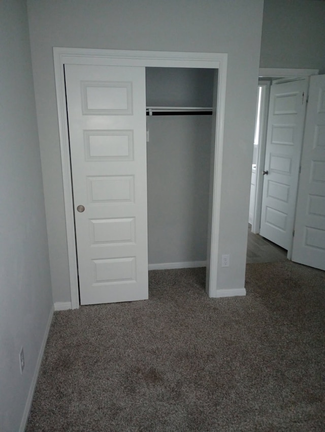 unfurnished bedroom with a closet, carpet flooring, and baseboards