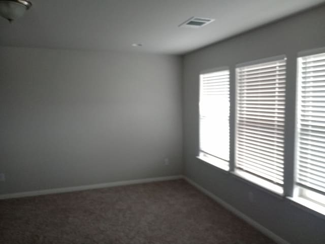 carpeted empty room featuring baseboards and visible vents